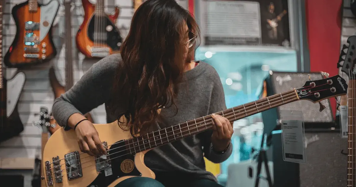 Woman playing bass guitar in music store